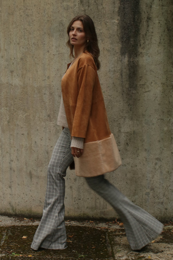 Secondhand Outfit: Kurzmantel aus Veloursleder in warmem Camelton mit kontrastierendem Fellbesatz, kombiniert mit Strick und karierter Hose – moderner, nachhaltiger Markenlook