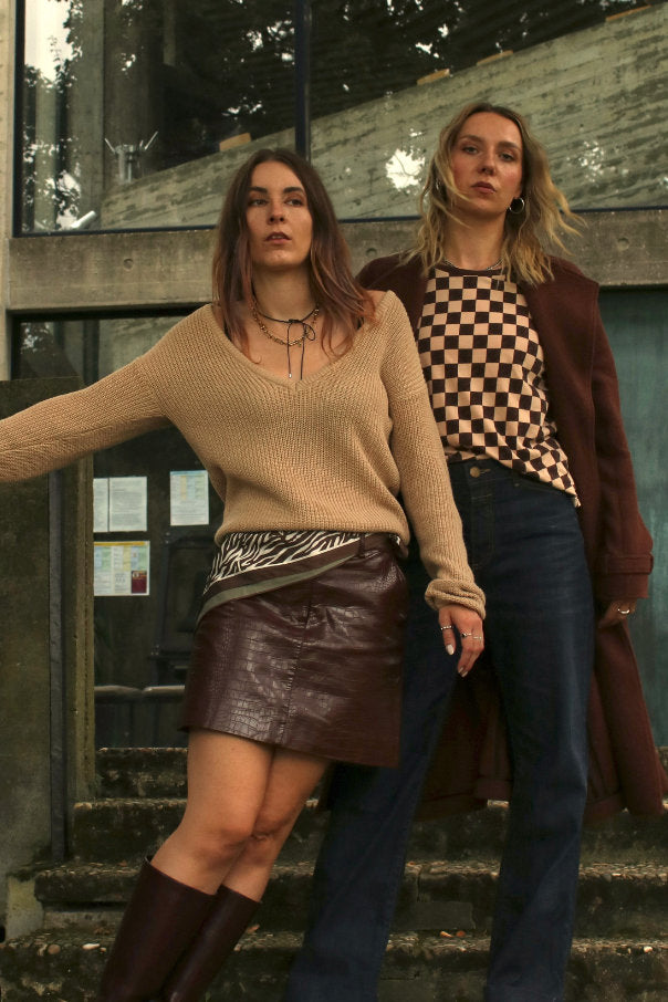 2 Frauen in herbstlichen Secondhand Outfits: Pullover, Lederrock und Stiefel, langer brauner Mantel T-Shirt mit Karo-Print und Dark Denim Jeans von Closed
